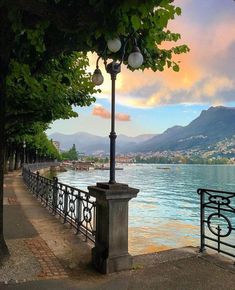 a lamp post next to the water with mountains in the background