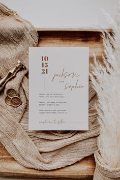 the wedding stationery is laid out on a wooden tray with two pairs of scissors