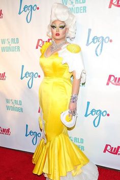 lady in yellow and white dress on red carpet with logo sign above her head at event