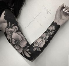 a woman's arm covered in black and white floral tattoo art design on her left arm