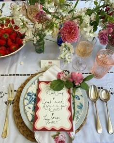 a place setting with strawberries and flowers on the table