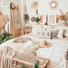 a bed with pillows and blankets on top of it in a room filled with plants