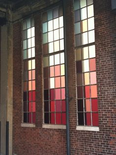 the side of a brick building with three windows and a bench in front of it