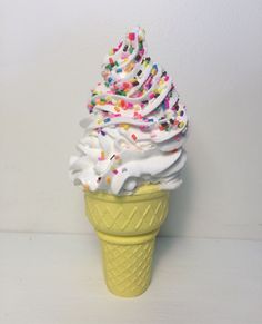 an ice cream cone with sprinkles and white frosting on it's top