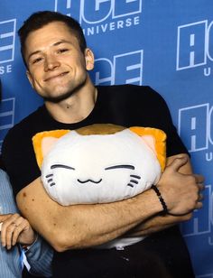 a man holding a stuffed cat in front of a blue wall with the words ice house on it