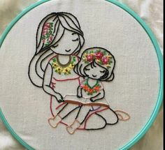 the embroidery on this hoop has been stitched to look like a mother holding her child