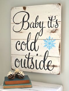 a wooden sign that says baby it's cold outside with snowflakes in the background