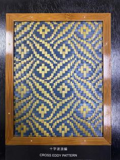 cross - edgy pattern in blue and yellow on black background with wooden frame for display