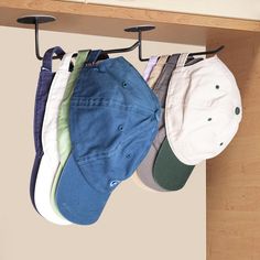 several hats are hanging from hooks on the wall next to a shelf with baseball caps