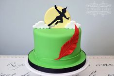 there is a green cake with a red feather on it and a person jumping in the air