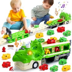 two young boys playing with toys on the floor and in front of them are green vehicles