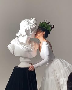 a woman in a white dress kissing a statue