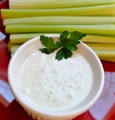 celery sticks and dip in a bowl on a red plate