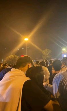 a crowd of people standing around each other at night