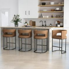 a kitchen with four stools in front of an island and counter top area,