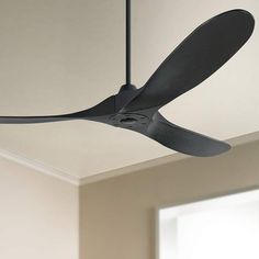 a black ceiling fan hanging from the ceiling in a room with white walls and windows