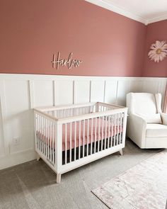 a baby's room with pink walls and white furniture