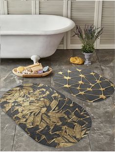 three bathroom rugs with gold leaf designs on the floor next to a bathtub