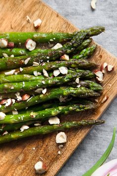 asparagus with almonds and garlic on a wooden cutting board next to flowers