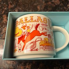 a coffee mug in a blue box with the word dalllasu on it's side