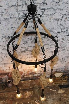 a chandelier with rope and lights hanging from it's sides in front of a brick wall