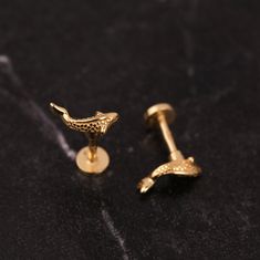 two gold cufflinks sitting next to each other on a black counter top,