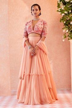 Peach two-tiered lehenga with gathered flare and frill detail. Comes with floral motif worked blouse and dupatta.
Component: 3
Embroidered
Neckline: V Neck
Sleeve Length: Half
Fabric: Blouse: Net; Lehenga: Chiffon; Dupatta: Net
Color: Peach
Plunging neck
Tiered lehenga
Gathered flare
Sheer panel
 - Aza Fashions Tiered Lehenga, Chiffon Lehenga, Peach Lehenga, Ridhi Mehra, Net Skirt, Net Blouses, Peach Blouse, Embroidered Crop Tops, Net Lehenga