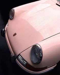 an old pink car is parked on the street