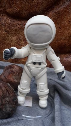 an astronaut figurine is posed next to some rocks and a rock on the ground