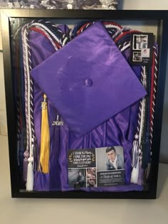 a purple graduation cap, tassels and other items are in a shadow box