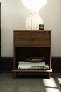 a bedroom with a bed, nightstand and lamp on the side table next to it