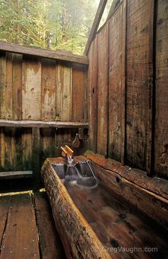 an old wooden bathtub in the corner of a room with wood walls and flooring