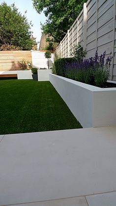 an outdoor garden with grass and white walls