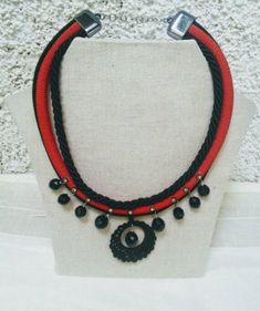 I lately discovered a small shop selling a range of cords and twine that the shopowners produce themselves. They use natural materials like cotton, linen, and plant-based silk. I bought some, and here is the result. A circular necklace with plant-based silk cords in red and black. I used three strands of cord and decorated them with gold and black bindis adorned with small silver crystals. I also added round black beads to the necklace's rim, which are attached using silver metal clasps.  The ce Handmade Black Nylon Cord Jewelry, Handmade Black Jewelry With Nylon Cord, Handmade Red Jewelry With Waxed Cord, Handmade Red Jewelry With Nylon Cord, Silk Cord Necklace, Unusual Necklace, Paper Bead Jewelry, Cocktail Jewelry, Wooden Necklace