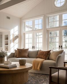 a living room filled with furniture and windows next to a table on top of a rug