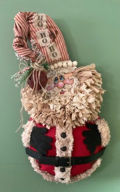 a stuffed santa clause hanging on the wall next to a green wall with a red and white striped jacket