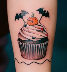 a cupcake with white frosting and spooky bats on the side of her leg