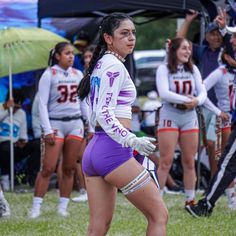 a woman in purple shorts and white shirt playing frisbee with other girls behind her