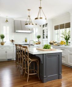 a large kitchen with white cabinets and wooden flooring, along with an island in the middle