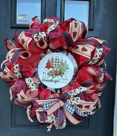 a red and black christmas wreath on the front door