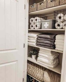 an organized closet with folded towels, baskets and toilet paper on the shelves in it