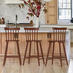 three wooden stools sit at the center of a kitchen island