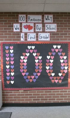 a bulletin board with hearts on it in front of a brick wall that says 100