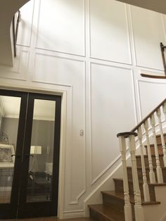 a staircase leading up to a bedroom with white walls and wood floors, next to a glass door