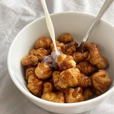 a white bowl filled with croissants next to a spoon