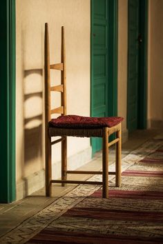 a wooden chair sitting on top of a rug next to a green door and doorway