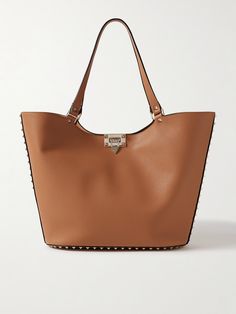 Those in the know will instantly recognize this tote as a Valentino Garavani design by the gold-tone 'Rockstud' embellishments. It's been made in Italy from textured-leather in a softly structured shape and has a flip lock at the open top. Stow everything you need, including an iPad, planner, water bottle and sunglasses case, inside. Luxury Formal Bags With Studs, Luxury Studded Formal Bags, Luxury Studded Shoulder Bag, Luxury Formal Shoulder Bag With Studs, Luxury Studded Shoulder Bag For Formal Occasions, Chic Studded Shoulder Bag, Formal Leather Bags With Studs, Luxury Studs Bags For Everyday, Elegant Leather Bag With Studs