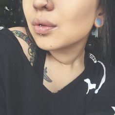 a woman with piercings on her nose looking at the camera while wearing a black shirt