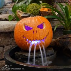 a carved pumpkin with glowing eyes and teeth on it's face is shown in front of a fountain