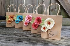 four small bags with paper flowers on them